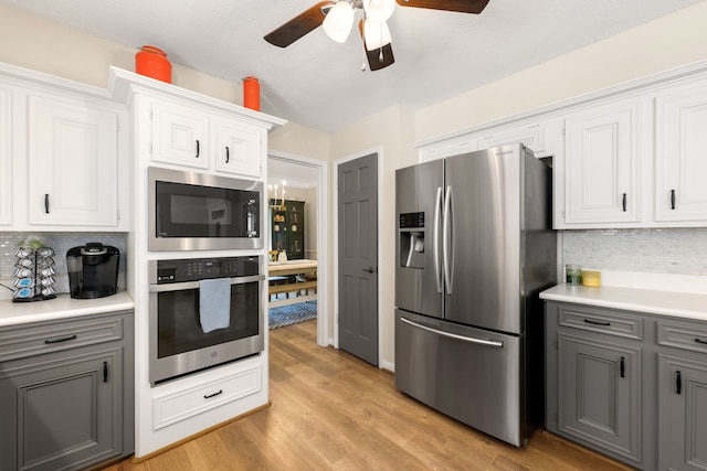 kitchen with gray cabinets, white cabinetry, decorative backsplash, and appliances with stainless steel finishes