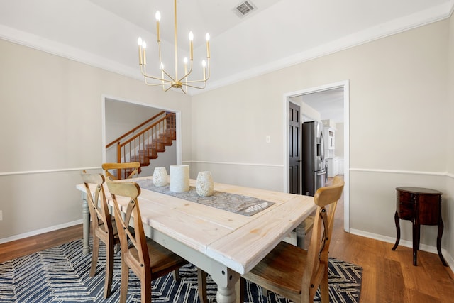 dining room with hardwood / wood-style floors, a notable chandelier, and crown molding