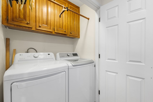 clothes washing area with washer and dryer and cabinets