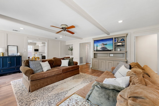 living room featuring ceiling fan, crown molding, beamed ceiling, and light hardwood / wood-style floors