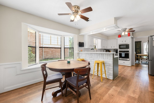 dining space with light wood-type flooring, a wealth of natural light, and ceiling fan