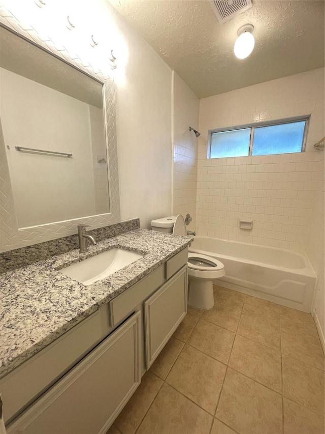 full bathroom with toilet, tile patterned flooring, a textured ceiling, and tiled shower / bath