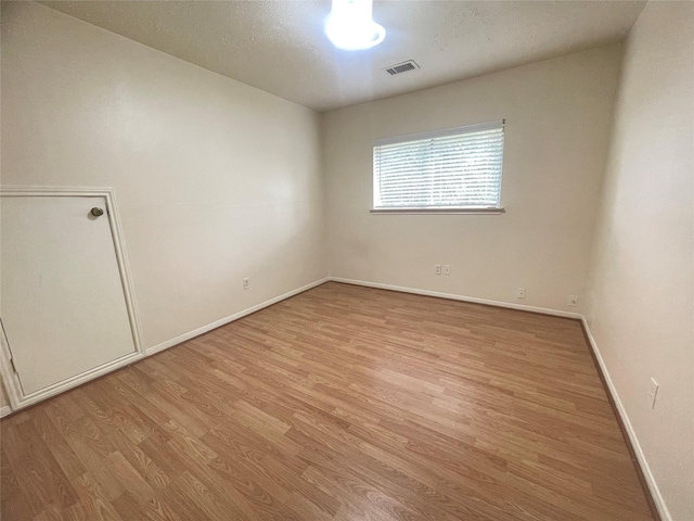 empty room featuring a textured ceiling and light hardwood / wood-style flooring