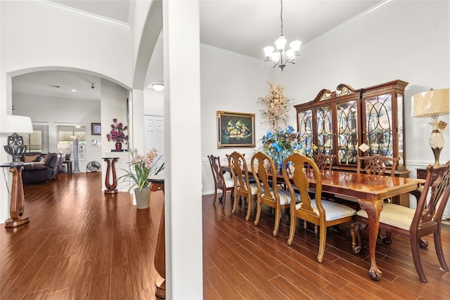 dining space featuring wood-type flooring, a towering ceiling, ornamental molding, and a notable chandelier