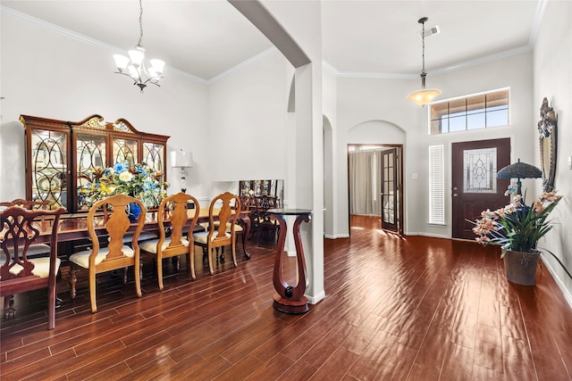 entryway with a high ceiling, ornamental molding, dark wood-type flooring, and a notable chandelier