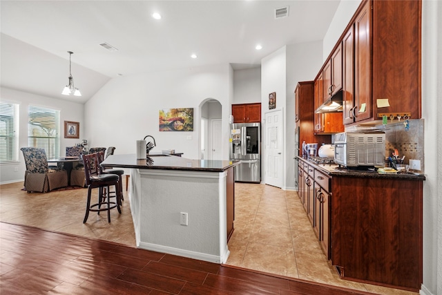 kitchen with vaulted ceiling, pendant lighting, a center island with sink, light hardwood / wood-style flooring, and stainless steel fridge with ice dispenser