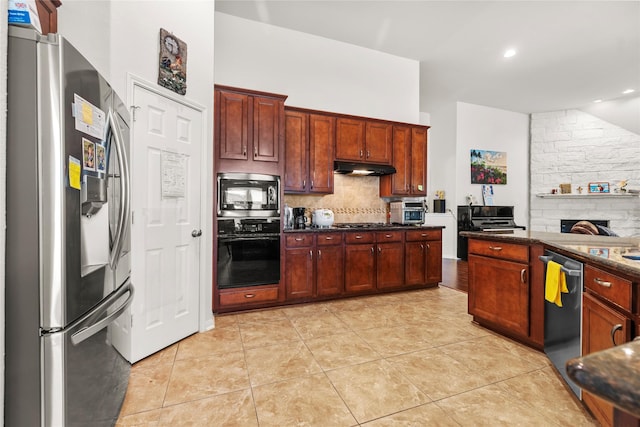 kitchen with appliances with stainless steel finishes, tasteful backsplash, light tile patterned floors, and dark stone countertops