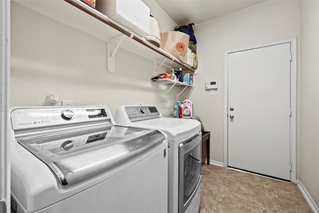 clothes washing area featuring light tile patterned floors and washer and dryer