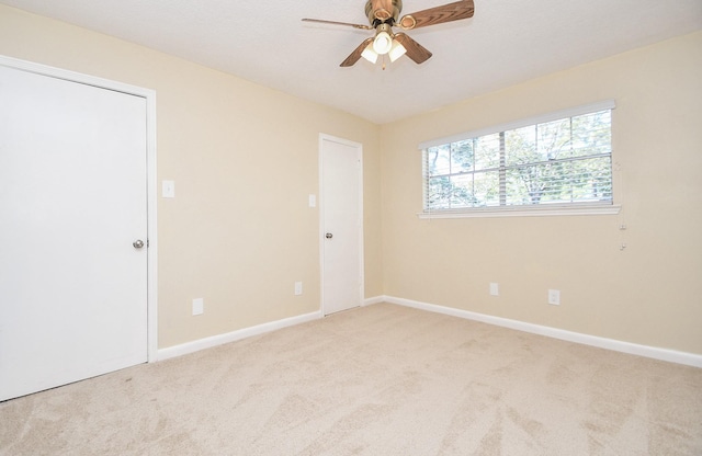 empty room with ceiling fan and light colored carpet