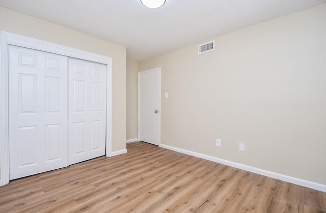 unfurnished bedroom with light hardwood / wood-style flooring and a closet