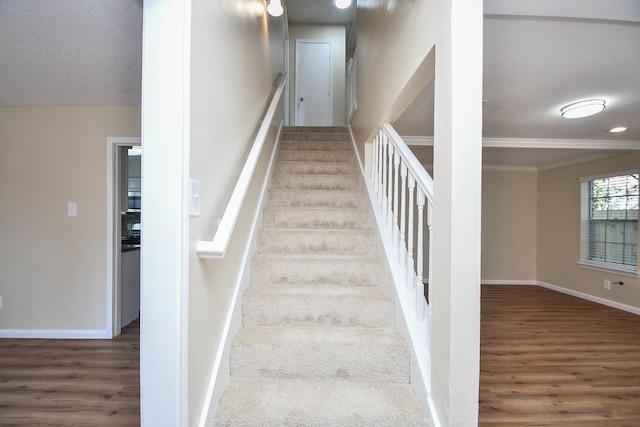 stairs with hardwood / wood-style floors, crown molding, and a textured ceiling