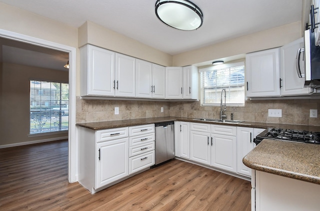 kitchen featuring white cabinetry, dishwasher, sink, light hardwood / wood-style flooring, and backsplash