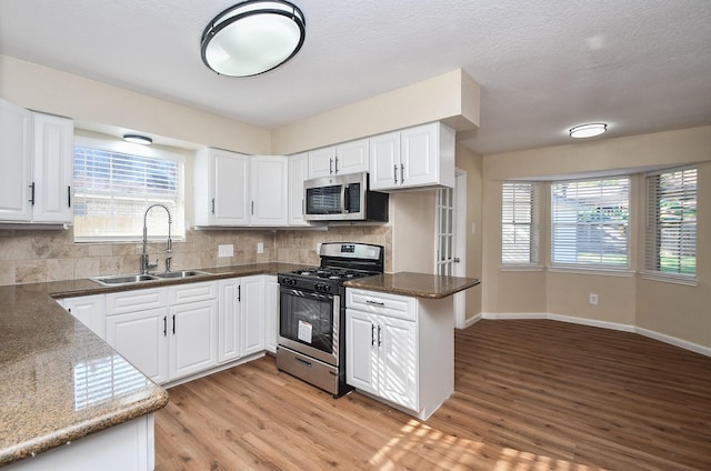 kitchen with white cabinets, kitchen peninsula, sink, and appliances with stainless steel finishes