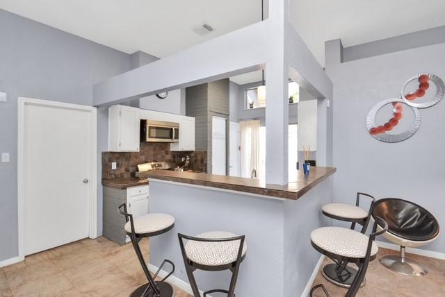 kitchen with a breakfast bar area, white cabinetry, kitchen peninsula, and tasteful backsplash