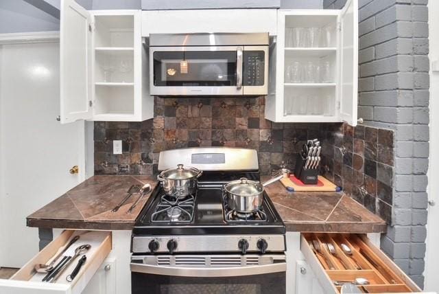 kitchen with tasteful backsplash, white cabinets, and appliances with stainless steel finishes