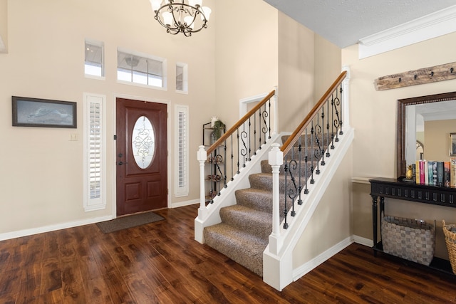 entryway with dark hardwood / wood-style flooring, a textured ceiling, a high ceiling, and a chandelier