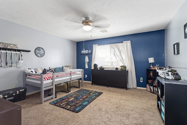 carpeted bedroom with ceiling fan and a textured ceiling