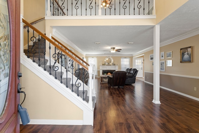 entrance foyer featuring decorative columns, crown molding, dark hardwood / wood-style flooring, and a textured ceiling