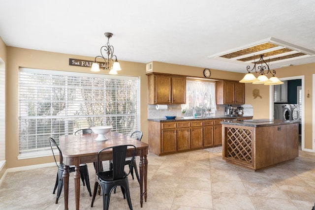 kitchen with sink, backsplash, a chandelier, pendant lighting, and a kitchen island