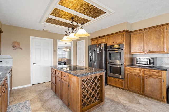 kitchen with a center island, hanging light fixtures, decorative backsplash, appliances with stainless steel finishes, and a notable chandelier