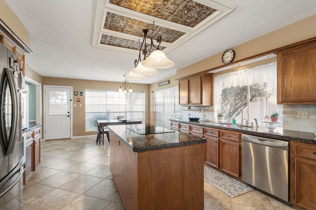 kitchen with tasteful backsplash, stainless steel appliances, sink, an inviting chandelier, and a center island