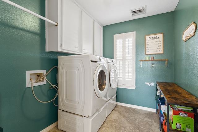 laundry area with washer and dryer, light tile patterned floors, and cabinets