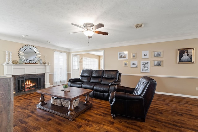 living room with a textured ceiling, ceiling fan, crown molding, and dark wood-type flooring