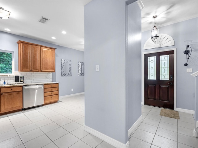 kitchen featuring pendant lighting, stainless steel dishwasher, light tile patterned floors, ornamental molding, and tasteful backsplash