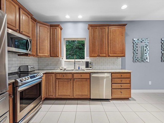 kitchen featuring sink, decorative backsplash, light tile patterned flooring, light stone counters, and stainless steel appliances