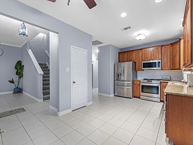 kitchen featuring backsplash, crown molding, sink, light stone counters, and stainless steel appliances