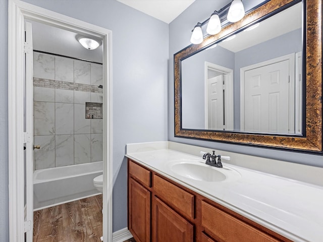 full bathroom with hardwood / wood-style floors, vanity, toilet, and tiled shower / bath combo