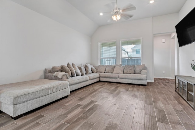 living room featuring ceiling fan, light wood-type flooring, and vaulted ceiling