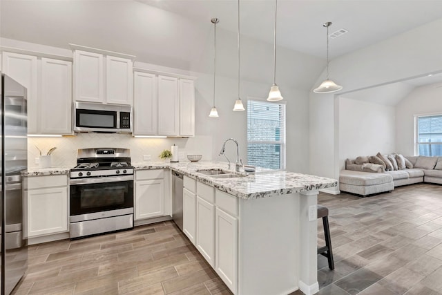 kitchen with kitchen peninsula, stainless steel appliances, sink, white cabinetry, and hanging light fixtures