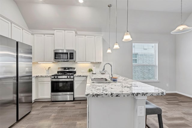 kitchen featuring stainless steel appliances, sink, decorative light fixtures, white cabinetry, and lofted ceiling