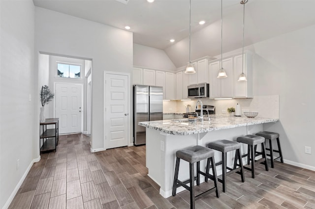 kitchen with white cabinetry, hardwood / wood-style floors, decorative light fixtures, and appliances with stainless steel finishes