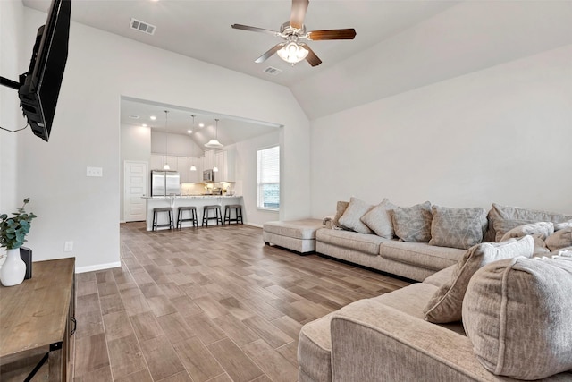 living room featuring wood-type flooring, vaulted ceiling, and ceiling fan