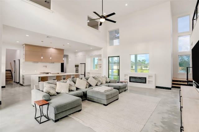 living room featuring ceiling fan and a towering ceiling