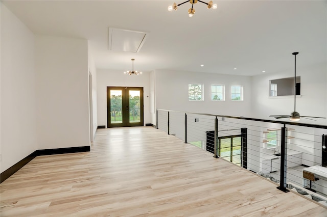 corridor with a chandelier, light wood-type flooring, and french doors