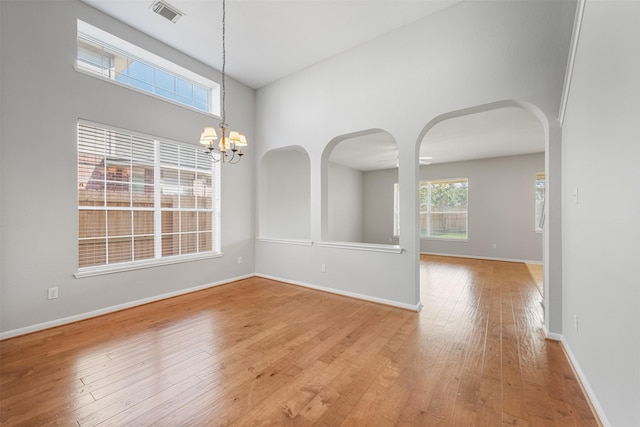 unfurnished room with a chandelier and light wood-type flooring