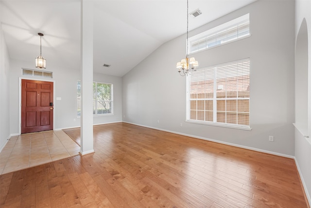 foyer with light hardwood / wood-style flooring, a chandelier, and vaulted ceiling