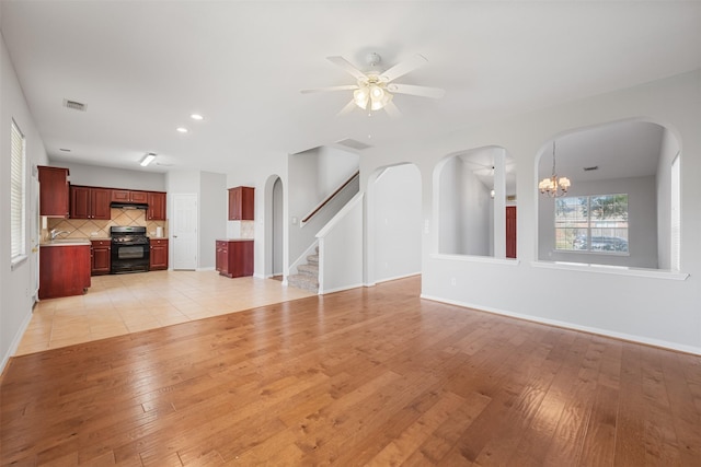 unfurnished living room featuring ceiling fan with notable chandelier, light hardwood / wood-style floors, and sink