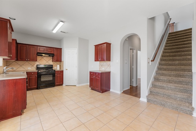 kitchen featuring light tile patterned flooring, black range with gas stovetop, backsplash, and sink