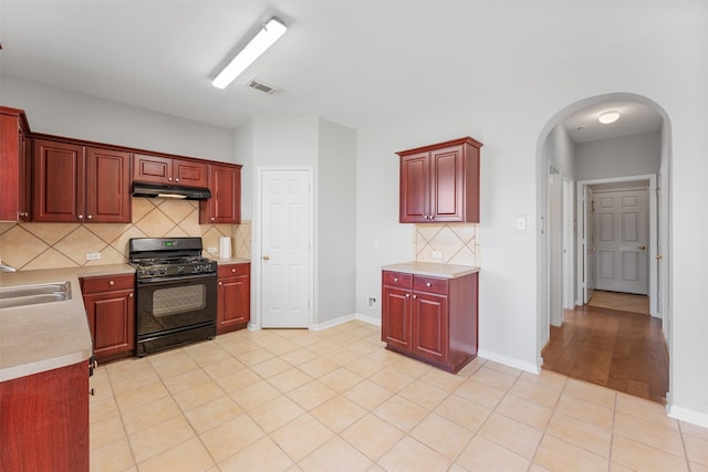 kitchen featuring light tile patterned flooring, gas stove, tasteful backsplash, and sink