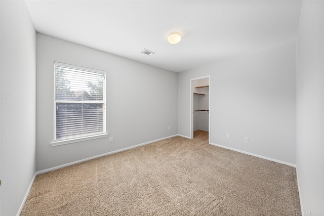 unfurnished bedroom featuring carpet flooring, a spacious closet, and a closet