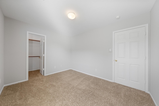 unfurnished bedroom with carpet flooring, a walk in closet, and a closet