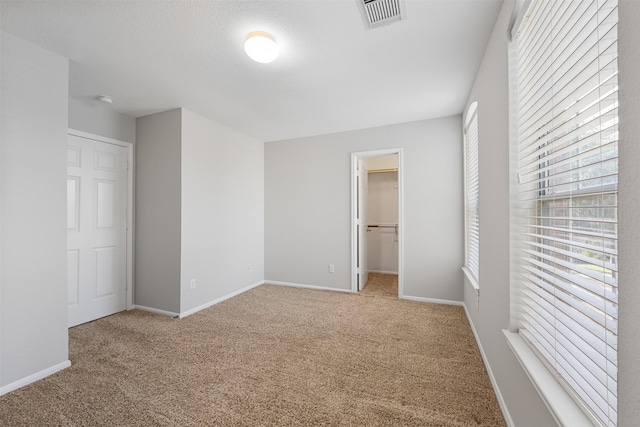 unfurnished bedroom featuring light carpet, a spacious closet, and a closet