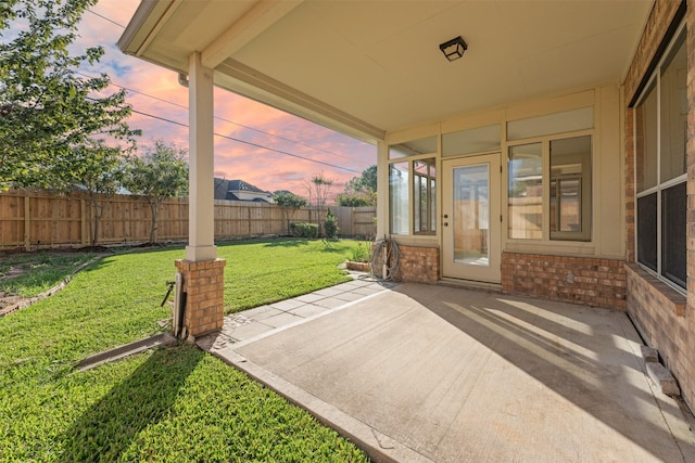 patio terrace at dusk featuring a yard