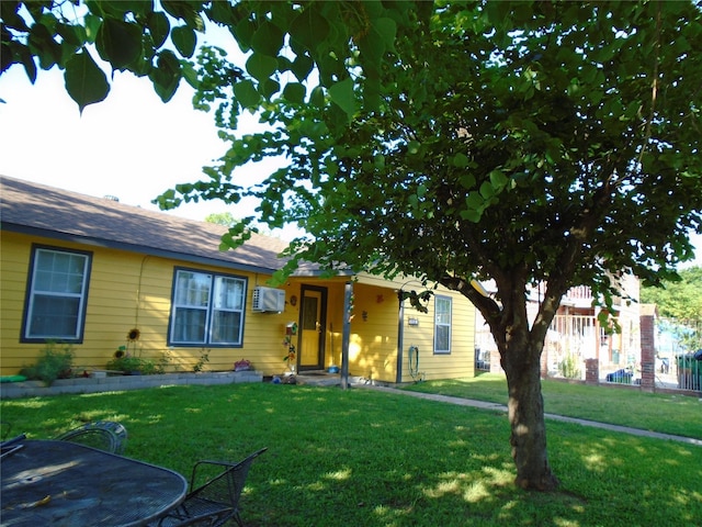 ranch-style home featuring a front yard and a wall mounted air conditioner