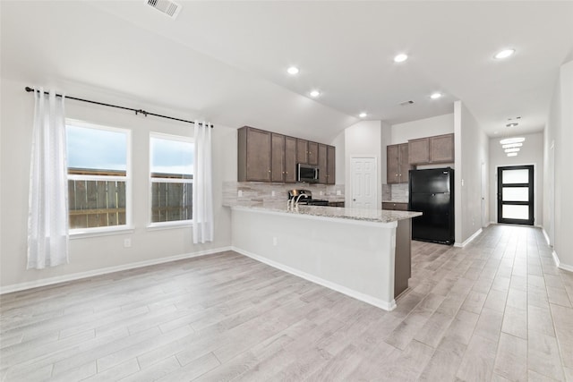 kitchen with kitchen peninsula, tasteful backsplash, stainless steel appliances, light hardwood / wood-style floors, and lofted ceiling