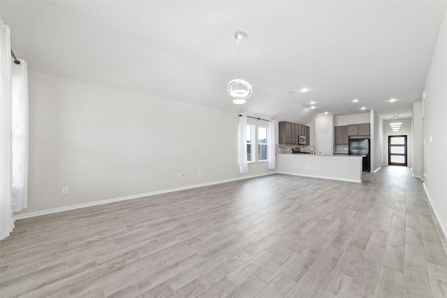 unfurnished living room featuring light wood-type flooring and vaulted ceiling